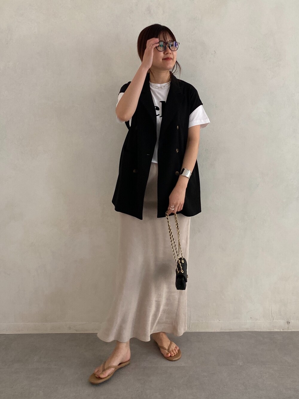 ブラック系のベスト、ホワイト系のTシャツ/カットソー、ブラック系のショルダーバッグを着用したレディースの春コーディネートの4枚目の写真