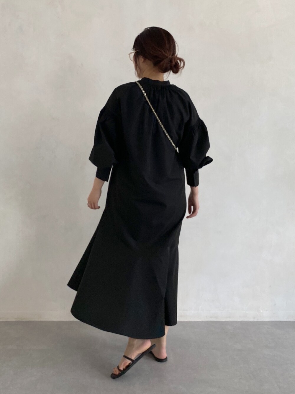 ブラック系のワンピース、ブルー系のショルダーバッグ、ゴールド系のメガネを着用したレディースの春コーディネートの2枚目の写真