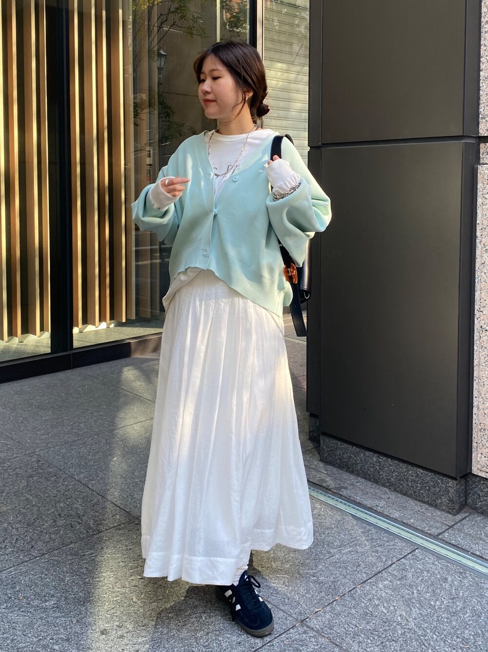 グリーン系のカーディガン/ボレロ、ホワイト系のスカートを着用したレディースの冬コーディネートの1枚目の写真
