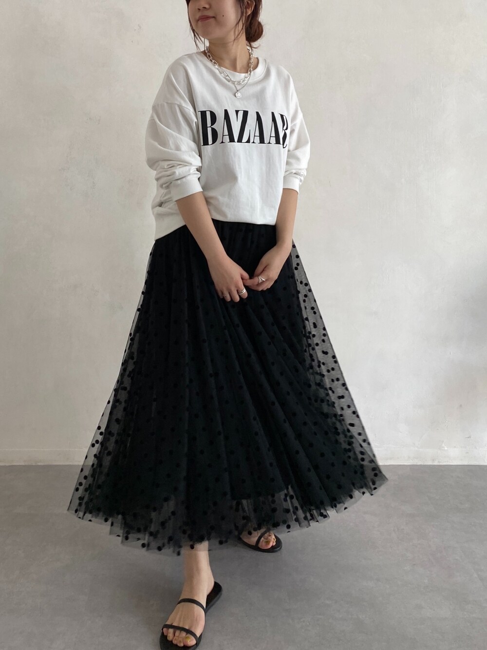 ホワイト系のTシャツ/カットソー、ブラック系のスカート、ブラック系のサンダルを着用したレディースの春コーディネートの4枚目の写真