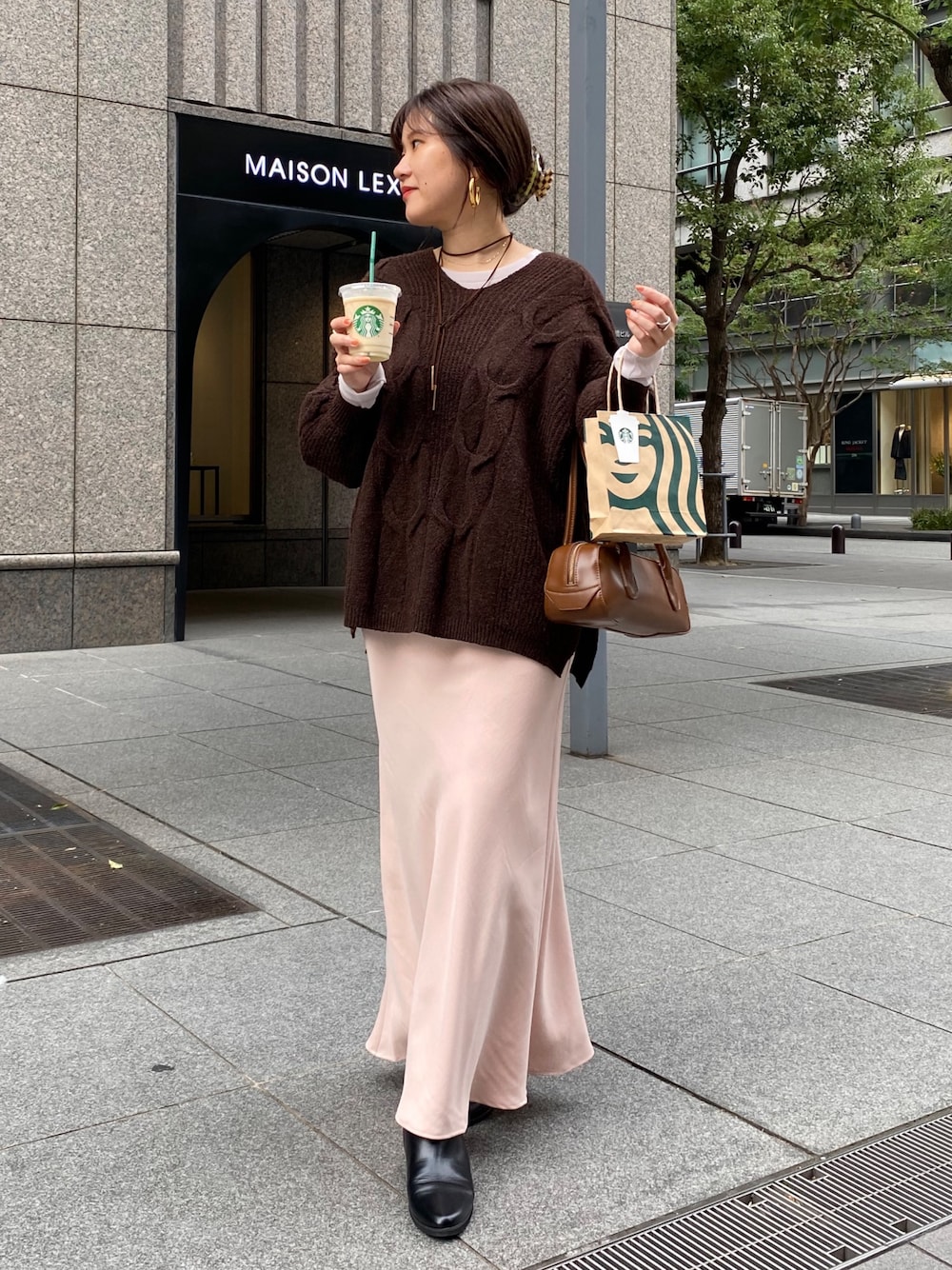 ブラウン系のニット/セーター、ピンク系のスカート、ブラック系のブーツを着用したレディースの冬コーディネートの1枚目の写真