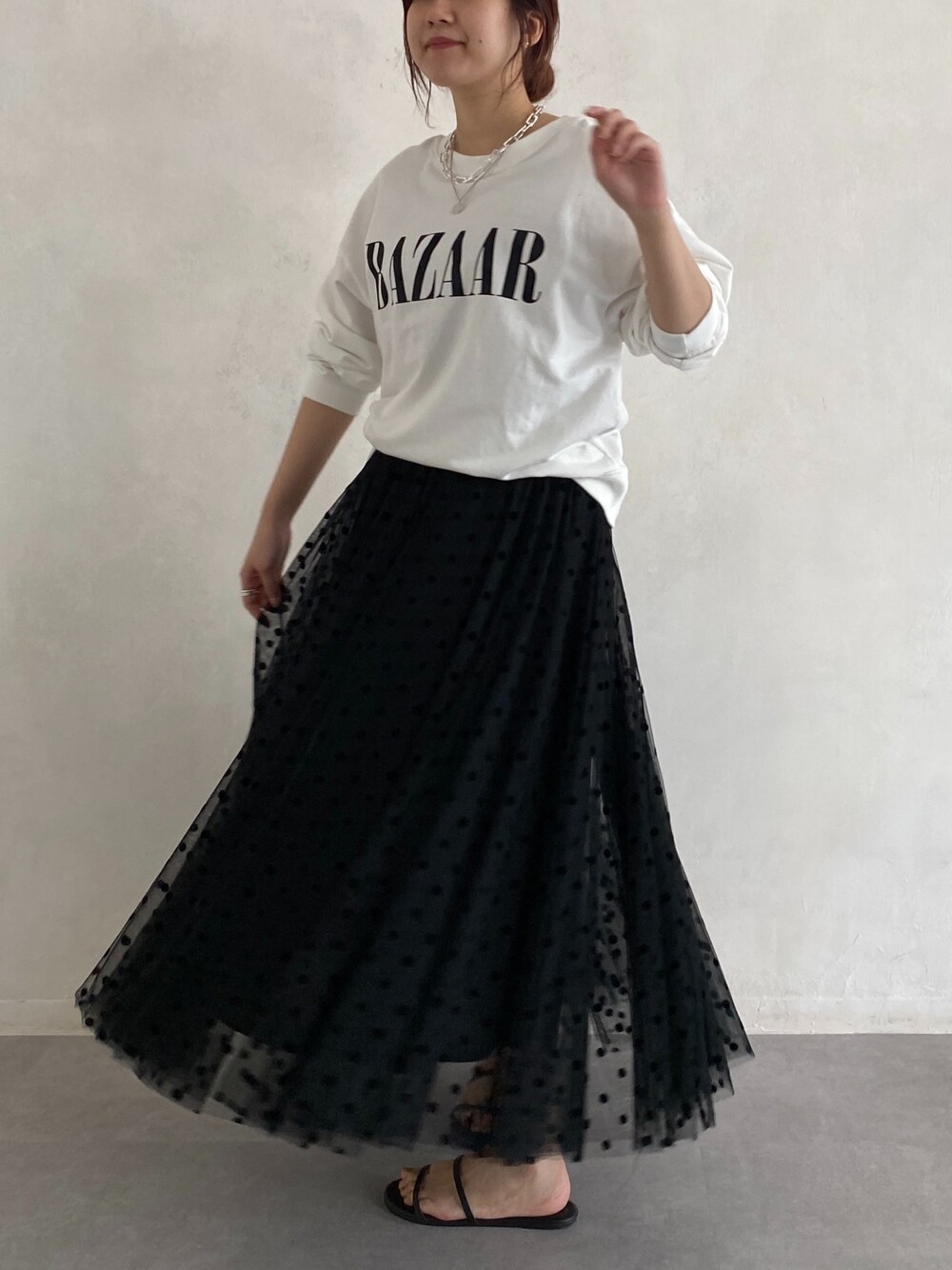 ホワイト系のTシャツ/カットソー、ブラック系のスカート、ブラック系のサンダルを着用したレディースの春コーディネートの5枚目の写真