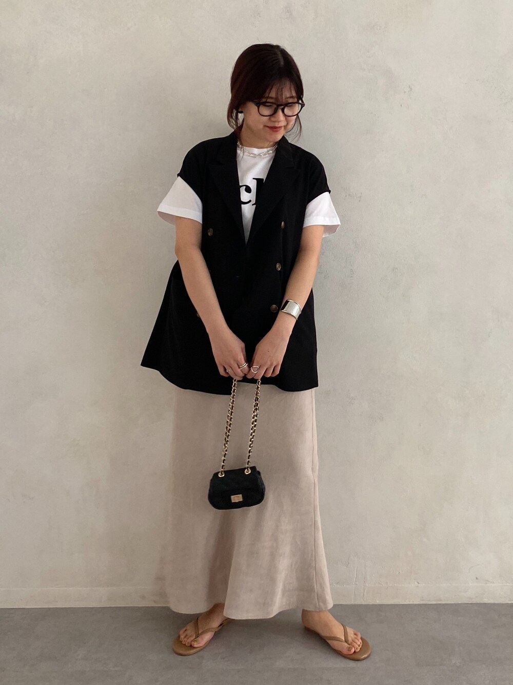 ブラック系のベスト、ホワイト系のTシャツ/カットソー、ブラック系のショルダーバッグを着用したレディースの春コーディネートの3枚目の写真