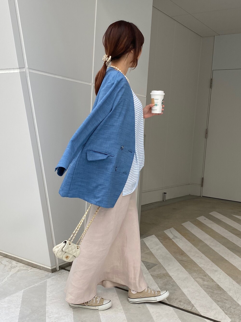 ブルー系のノーカラージャケット、ブルー系のTシャツ/カットソー、ベージュ系のスカートを着用したレディースの春コーディネートの4枚目の写真