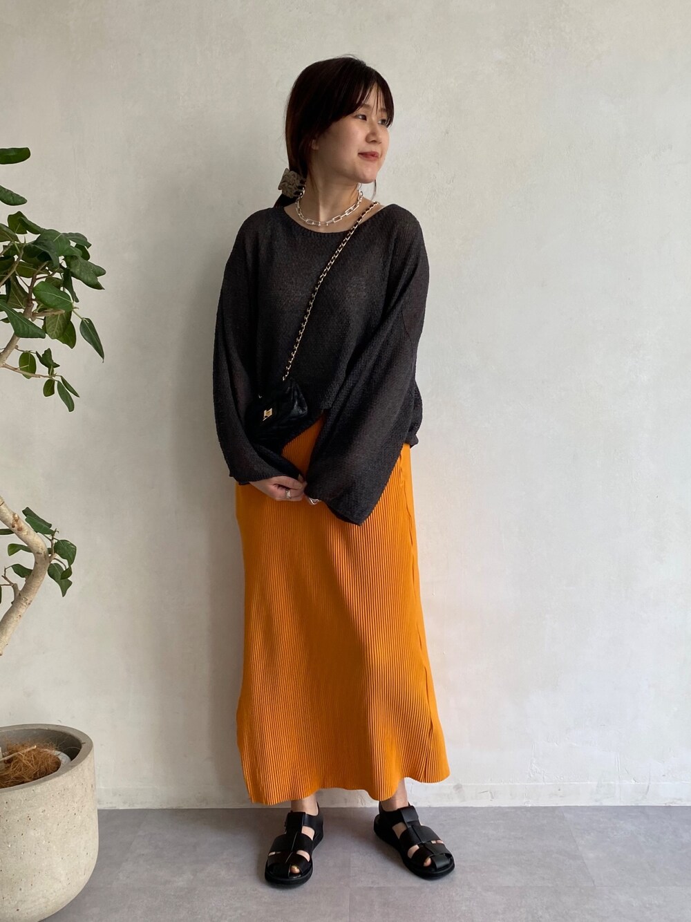 グレー系のニット/セーター、オレンジ系のスカート、ブラック系のその他シューズを着用したレディースの春コーディネートの2枚目の写真