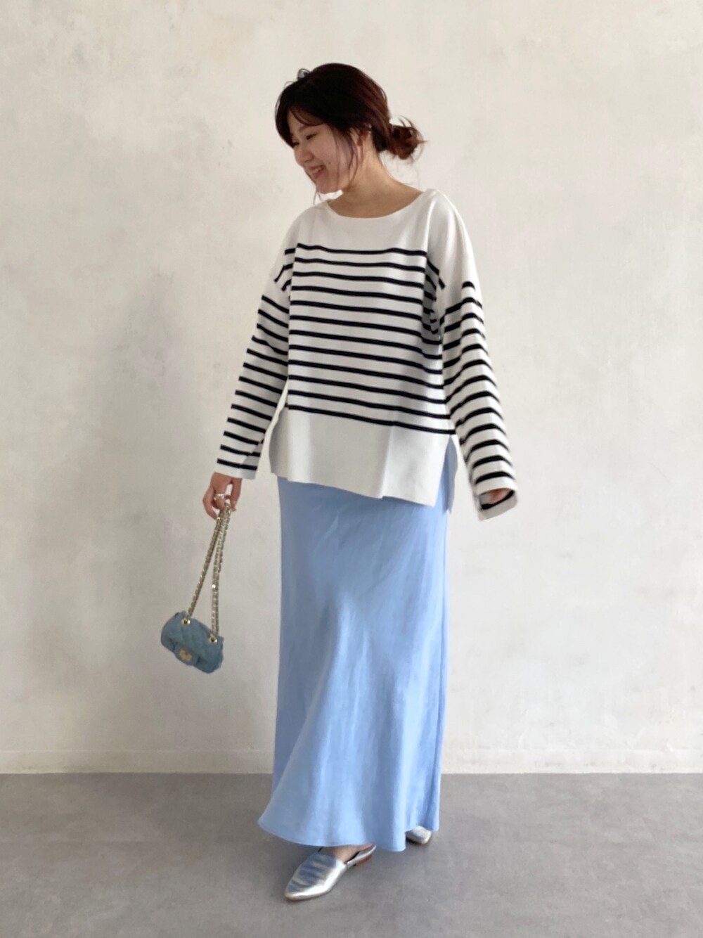 ブラック系のニット/セーター、ブルー系のスカート、ブルー系のショルダーバッグを着用したレディースの春コーディネートの5枚目の写真
