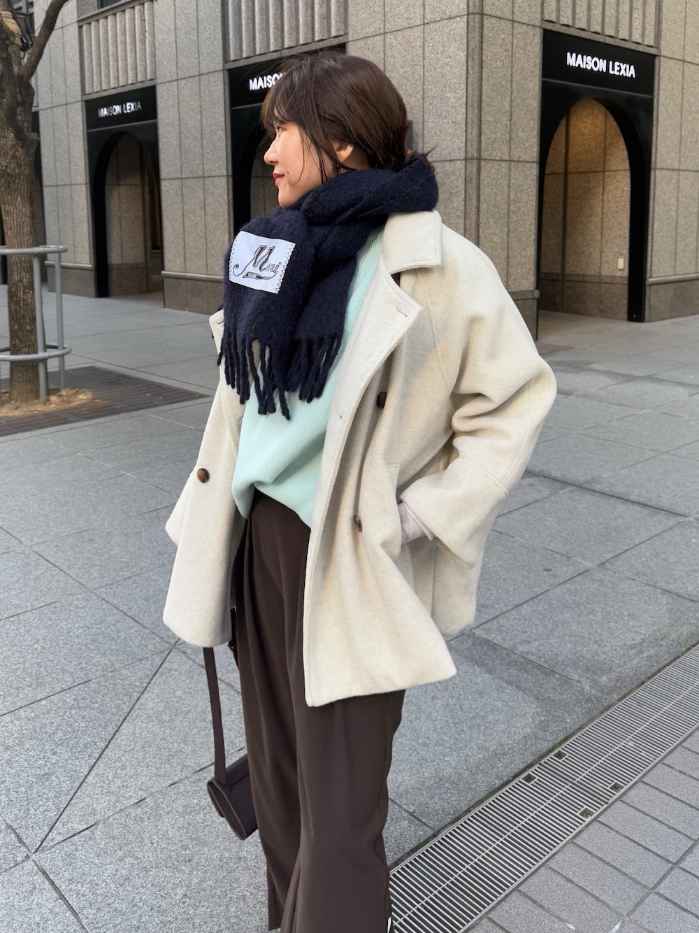 グリーン系のニット/セーター、ブラウン系のスラックス、グレー系のTシャツ/カットソーを着用したレディースの冬コーディネートの1枚目の写真