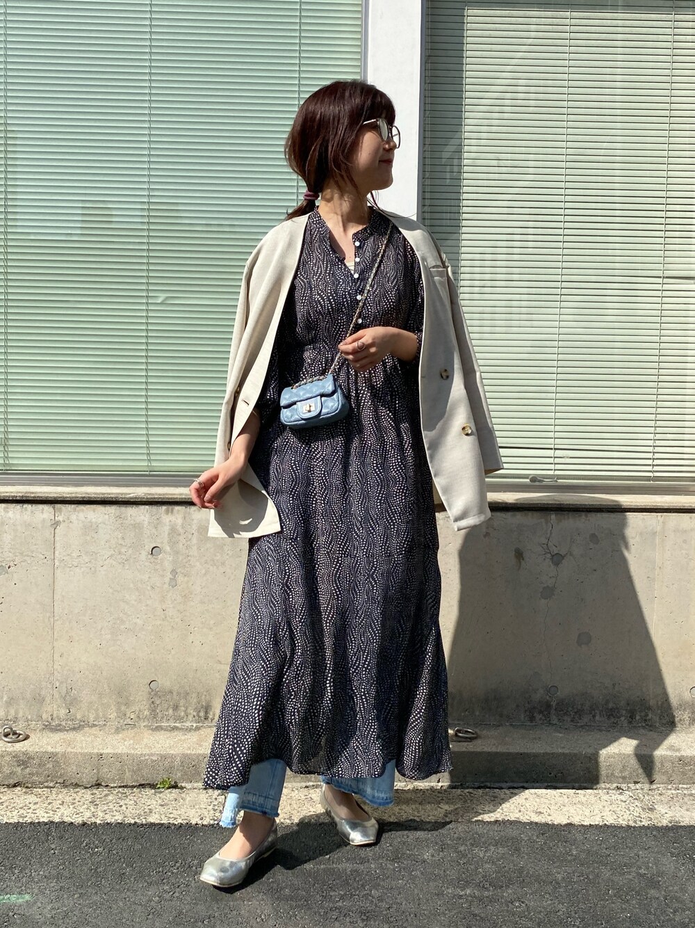 ベージュ系のノーカラージャケット、ブルー系のショルダーバッグ、ホワイト系のワンピースを着用したレディースの春コーディネートの2枚目の写真