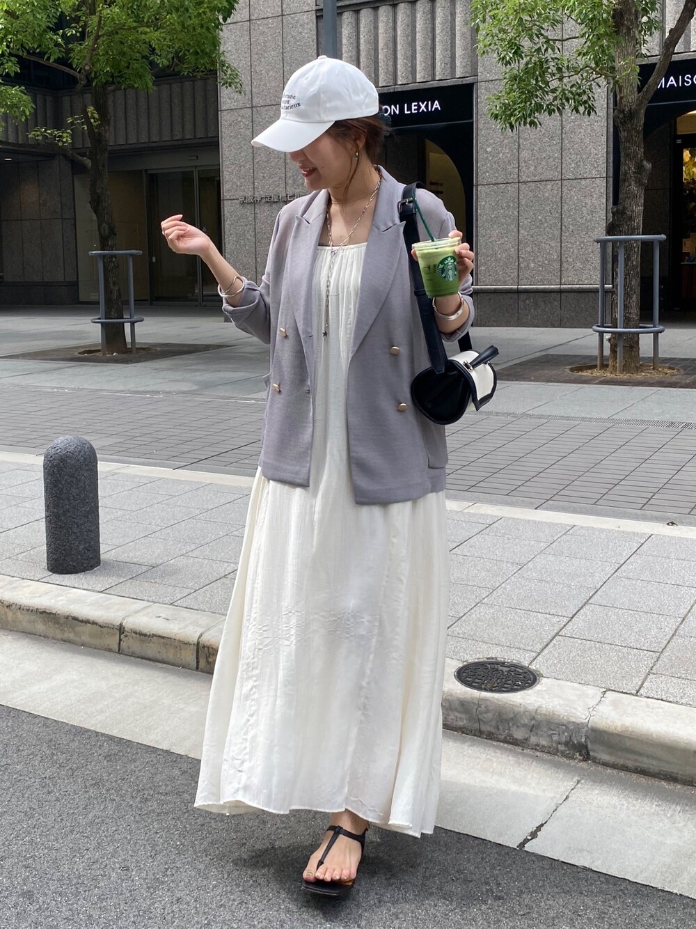 ブルー系のテーラードジャケット、ホワイト系のワンピース、ブラウン系のショルダーバッグを着用したレディースの春コーディネートの1枚目の写真