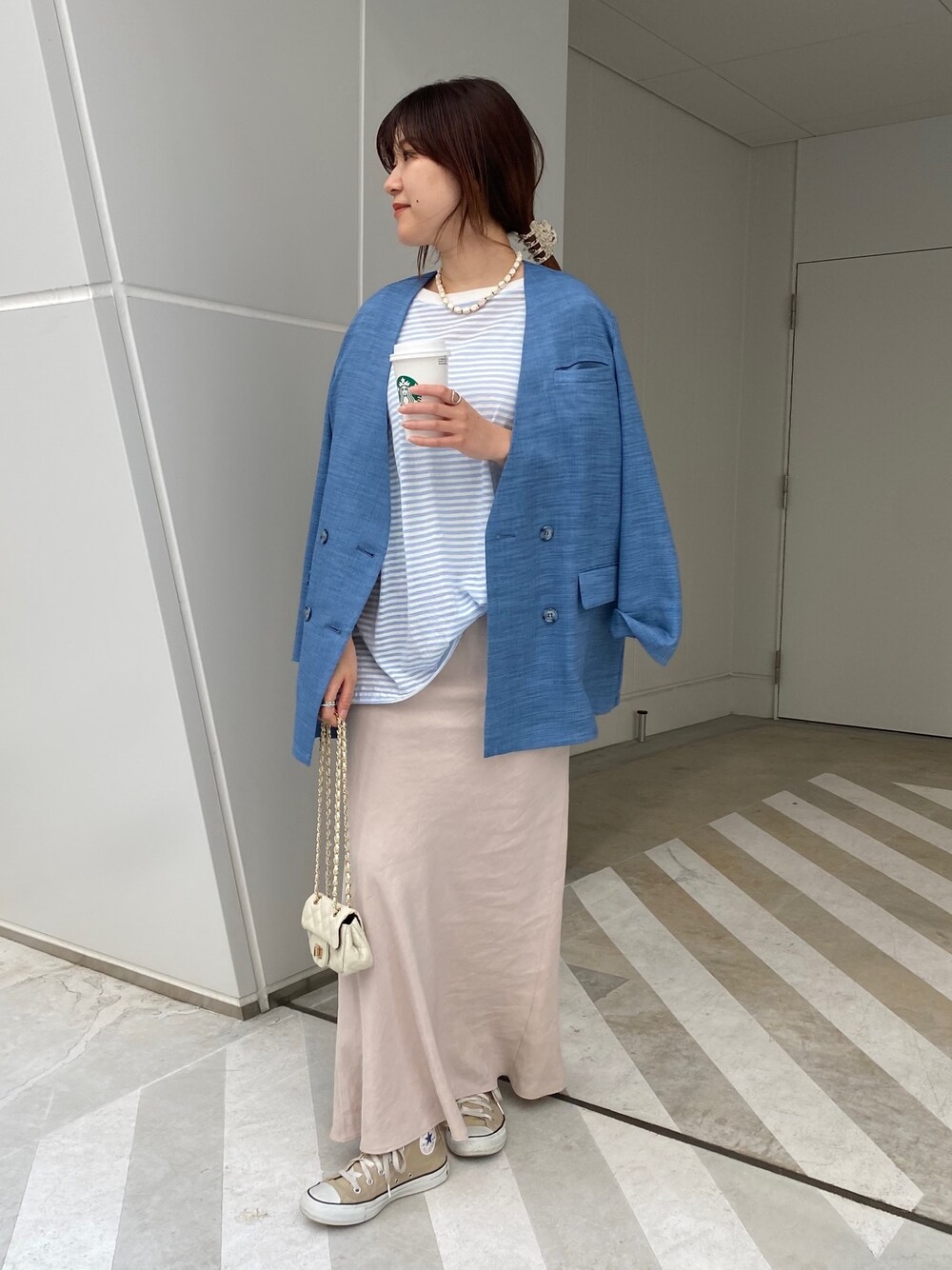 ブルー系のノーカラージャケット、ブルー系のTシャツ/カットソー、ベージュ系のスカートを着用したレディースの春コーディネートの3枚目の写真