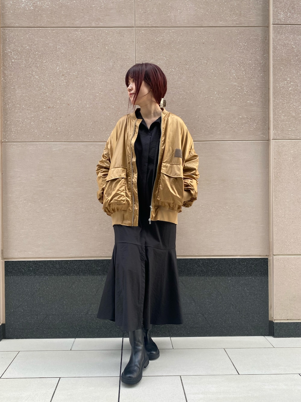 イエロー系のMA-1、ブラック系のワンピース、ブラック系のブーツを着用したレディースの秋コーディネートの1枚目の写真