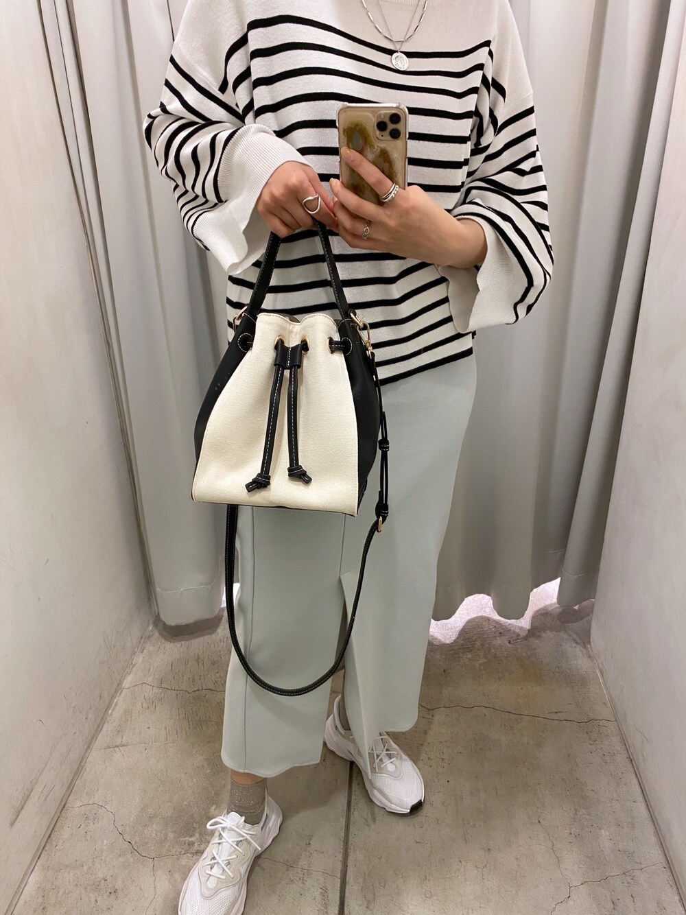 ブラック系のニット/セーター、ブルー系のスカート、ホワイト系のトートバッグを着用したレディースの冬コーディネートの3枚目の写真