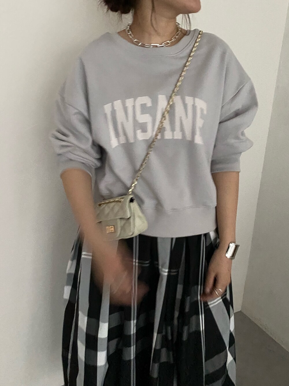 ベージュ系のTシャツ/カットソー、ブラック系のスカート、ホワイト系のショルダーバッグを着用したレディースの春コーディネートの4枚目の写真