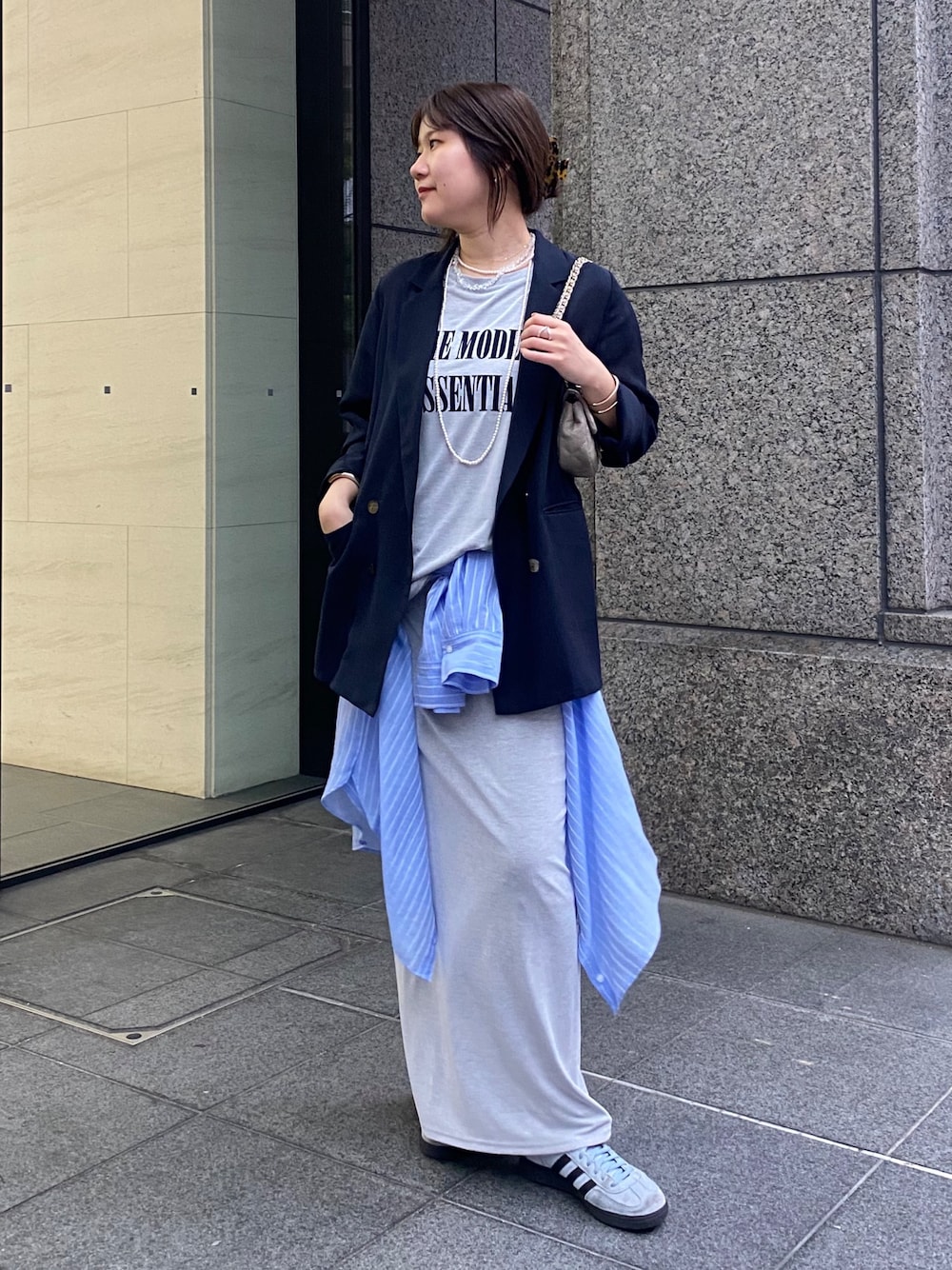 ブルー系のテーラードジャケット、グレー系のTシャツ/カットソー、グレー系のスカートを着用したレディースの春コーディネートの1枚目の写真