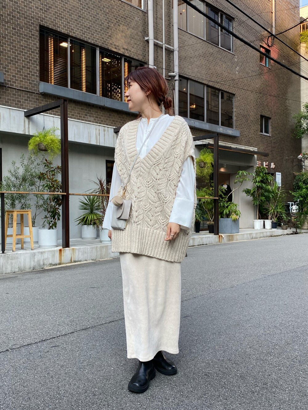 ベージュ系のニット/セーター、ホワイト系のシャツ/ブラウス、ベージュ系のショルダーバッグを着用したレディースの秋コーディネートの1枚目の写真
