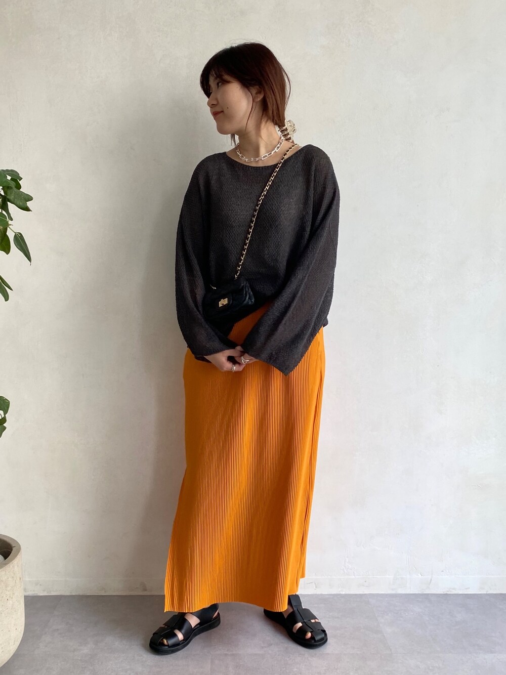 グレー系のニット/セーター、オレンジ系のスカート、ブラック系のその他シューズを着用したレディースの春コーディネートの5枚目の写真