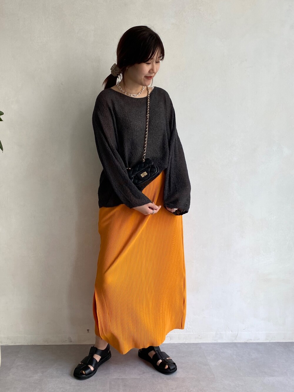 グレー系のニット/セーター、オレンジ系のスカート、ブラック系のその他シューズを着用したレディースの春コーディネートの4枚目の写真