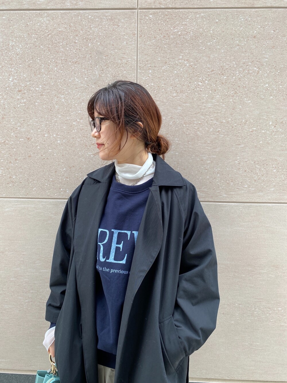 ブラック系のステンカラーコート、ブルー系のスウェット、グリーン系のショルダーバッグを着用したレディースの冬コーディネートの5枚目の写真