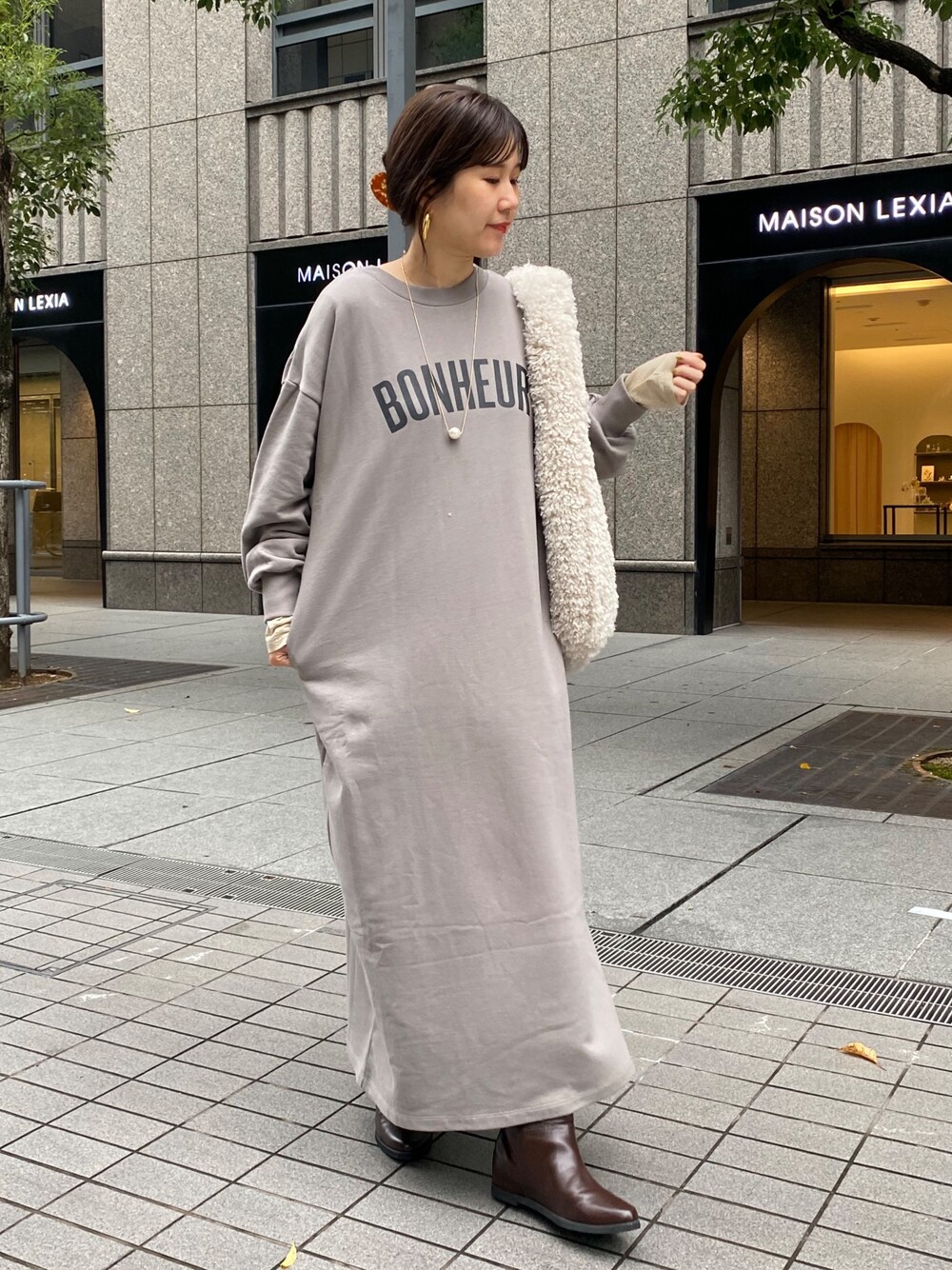 グレー系のワンピース、ブラウン系のブーツ、ゴールド系のTシャツ/カットソーを着用したレディースの秋コーディネートの1枚目の写真