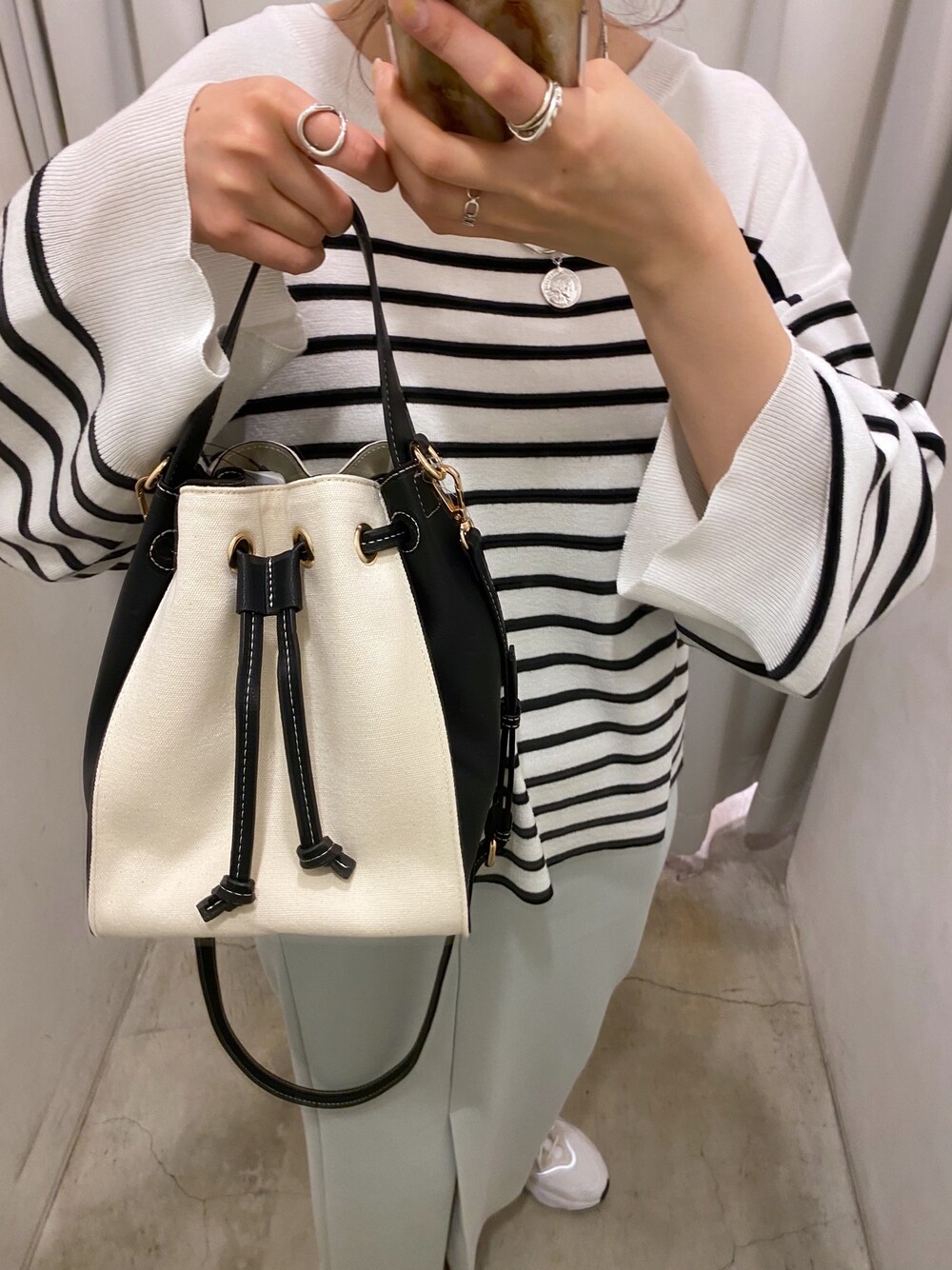 ブラック系のニット/セーター、ブルー系のスカート、ホワイト系のトートバッグを着用したレディースの冬コーディネートの5枚目の写真