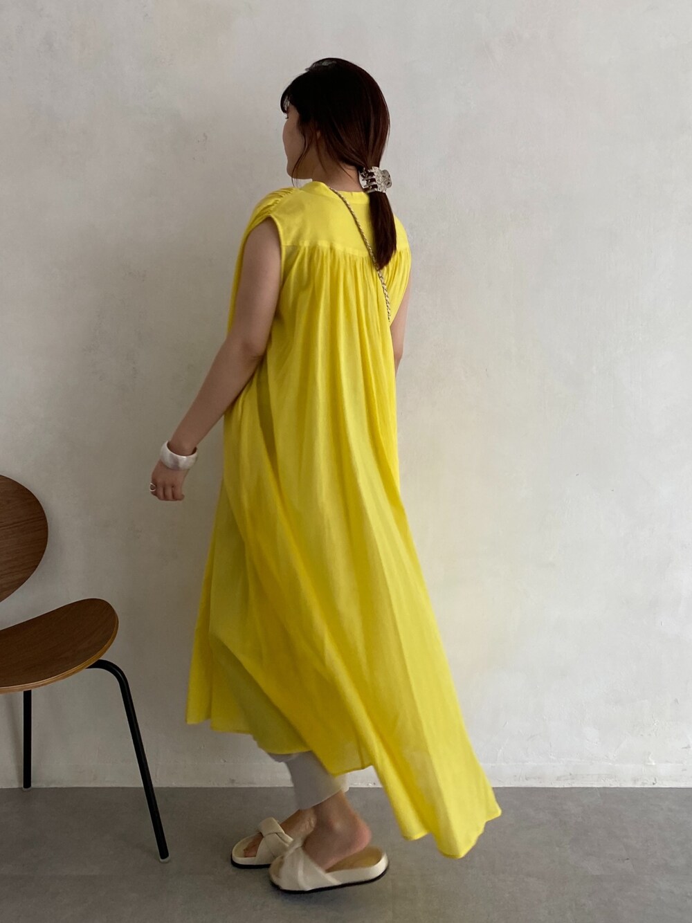 イエロー系のワンピース、ホワイト系のショルダーバッグ、ホワイト系のその他シューズを着用したレディースの春コーディネートの3枚目の写真