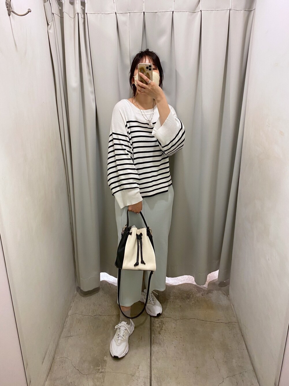 ブラック系のニット/セーター、ブルー系のスカート、ホワイト系のトートバッグを着用したレディースの冬コーディネートの2枚目の写真