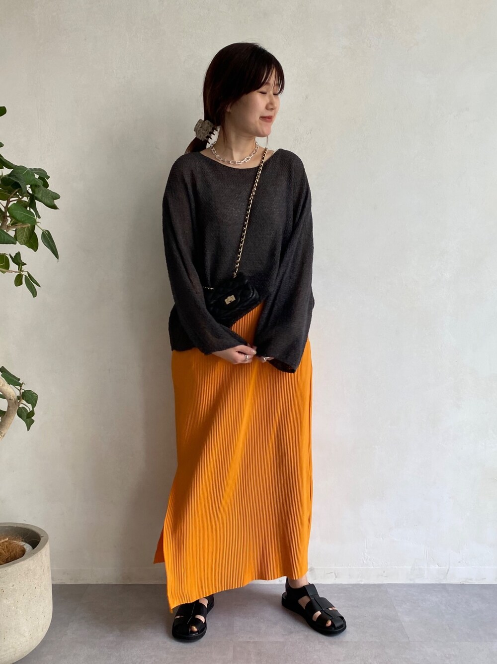 グレー系のニット/セーター、オレンジ系のスカート、ブラック系のその他シューズを着用したレディースの春コーディネートの3枚目の写真