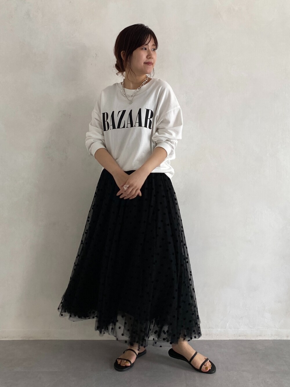 ホワイト系のTシャツ/カットソー、ブラック系のスカート、ブラック系のサンダルを着用したレディースの春コーディネートの3枚目の写真