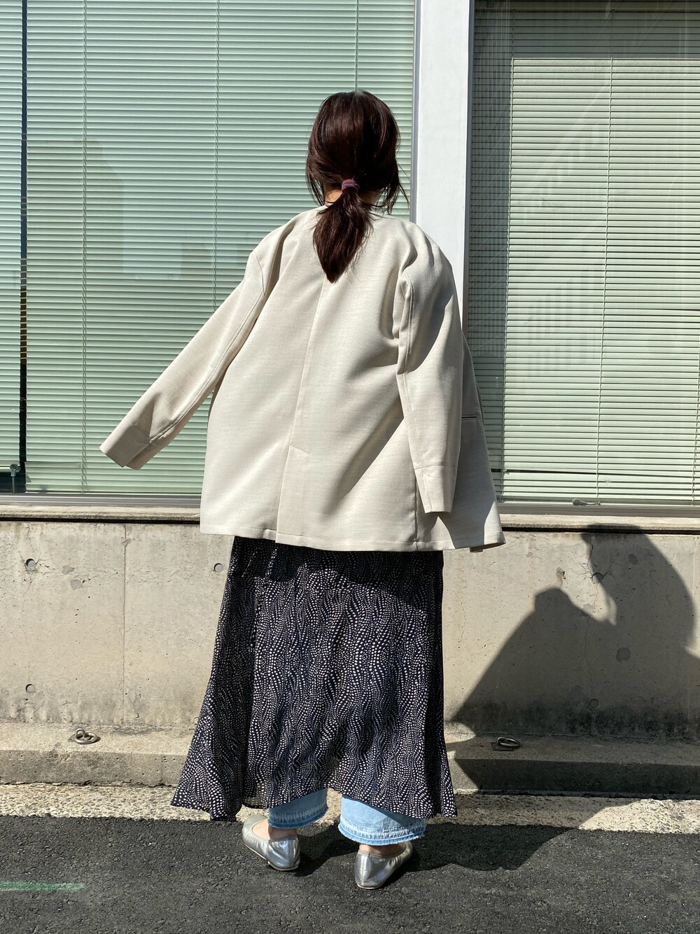 ベージュ系のノーカラージャケット、ブルー系のショルダーバッグ、ホワイト系のワンピースを着用したレディースの春コーディネートの4枚目の写真