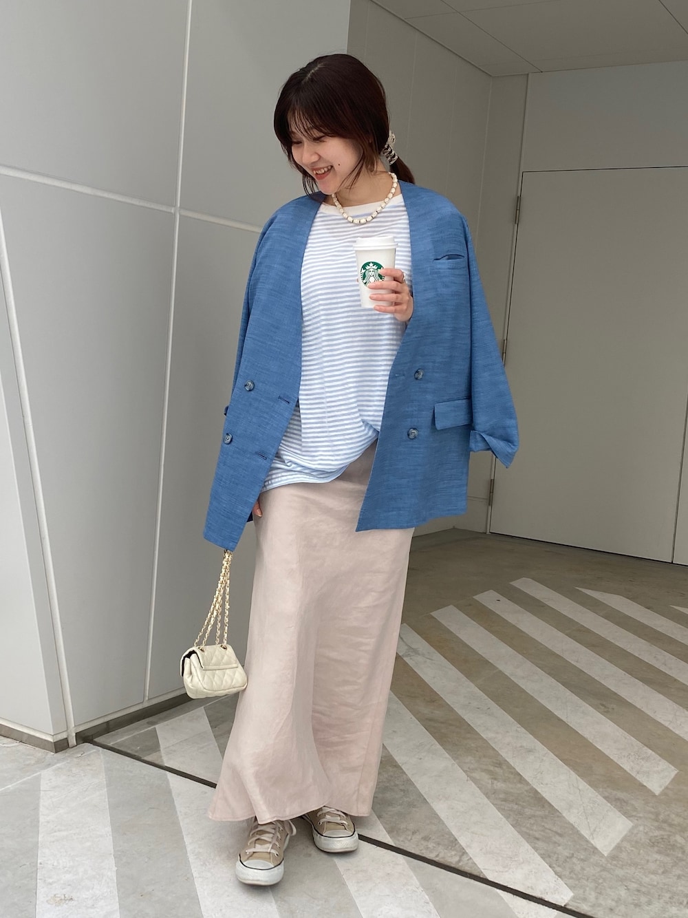 ブルー系のノーカラージャケット、ブルー系のTシャツ/カットソー、ベージュ系のスカートを着用したレディースの春コーディネートの5枚目の写真