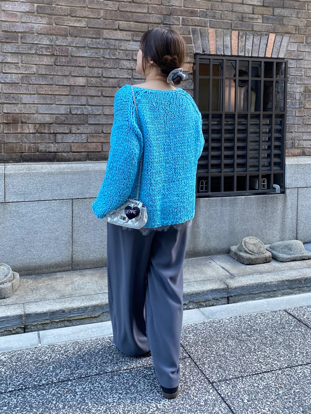 ブルー系のニット/セーター、グレー系のTシャツ/カットソー、グレー系のスラックスを着用したレディースの冬コーディネートの1枚目の写真