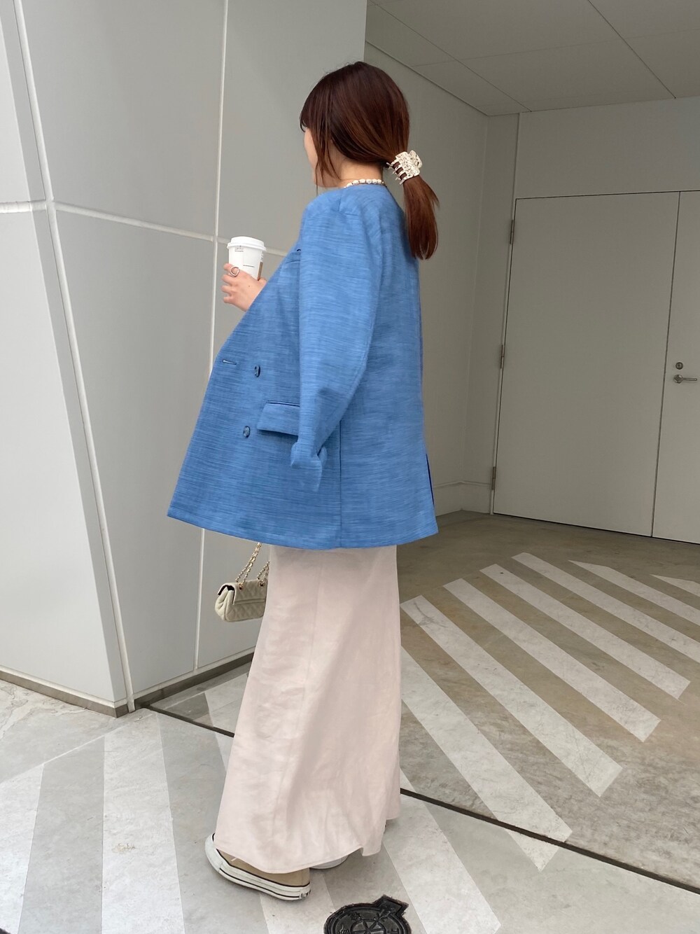 ブルー系のノーカラージャケット、ブルー系のTシャツ/カットソー、ベージュ系のスカートを着用したレディースの春コーディネートの5枚目の写真