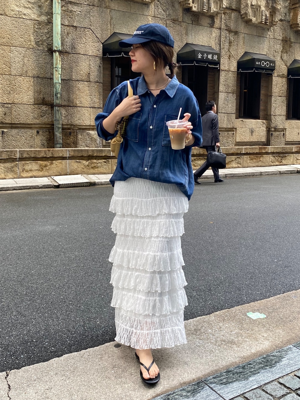 ブルー系のシャツ/ブラウス、ホワイト系のスカート、ゴールド系のネックレスを着用したレディースの春コーディネートの1枚目の写真