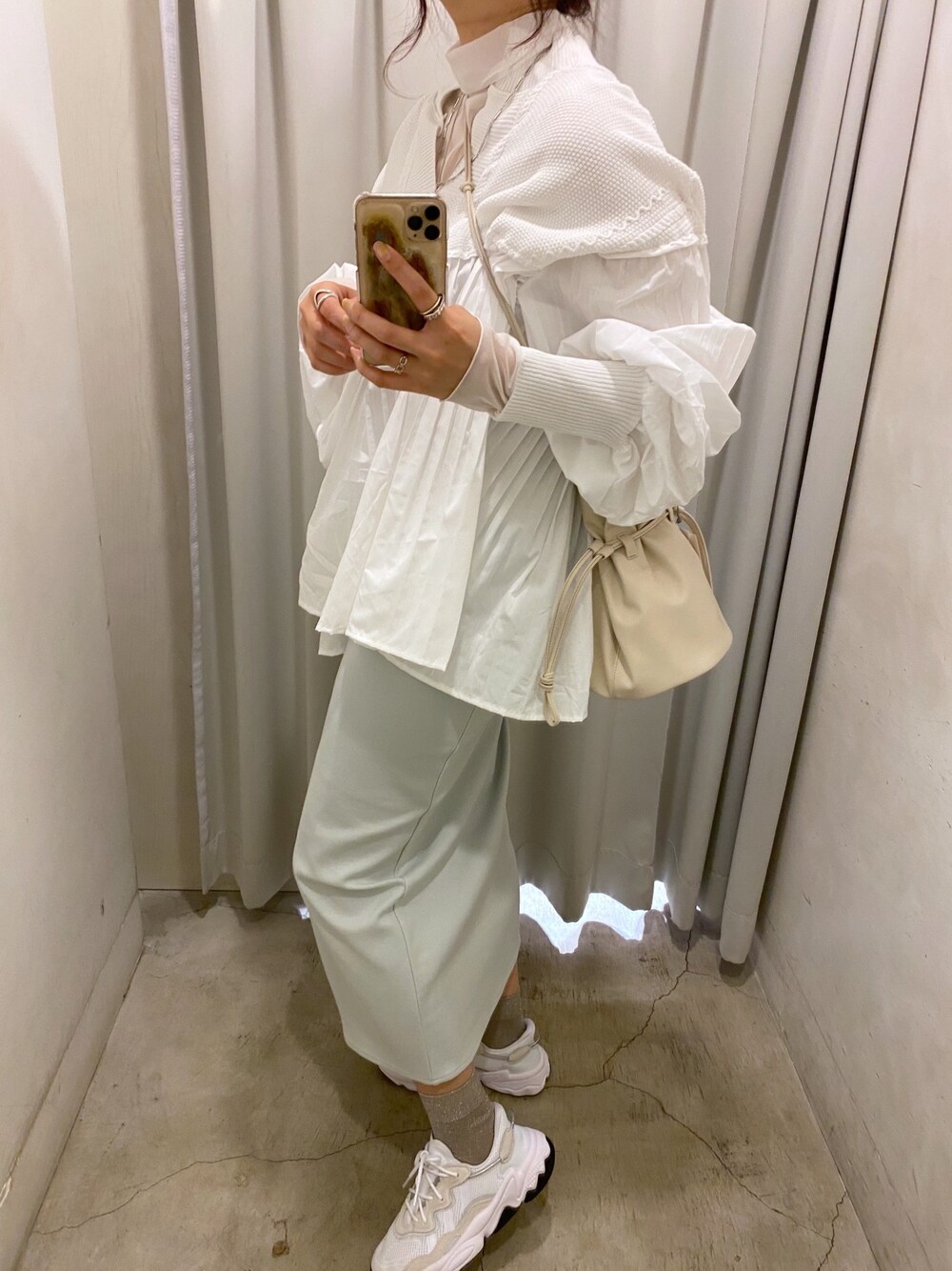 ホワイト系のTシャツ/カットソー、ベージュ系のステンカラーコート、ホワイト系のニット/セーターを着用したレディースの冬コーディネートの3枚目の写真