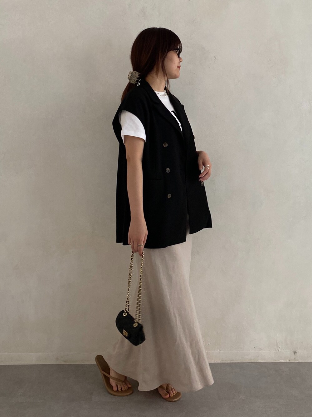 ブラック系のベスト、ホワイト系のTシャツ/カットソー、ブラック系のショルダーバッグを着用したレディースの春コーディネートの5枚目の写真