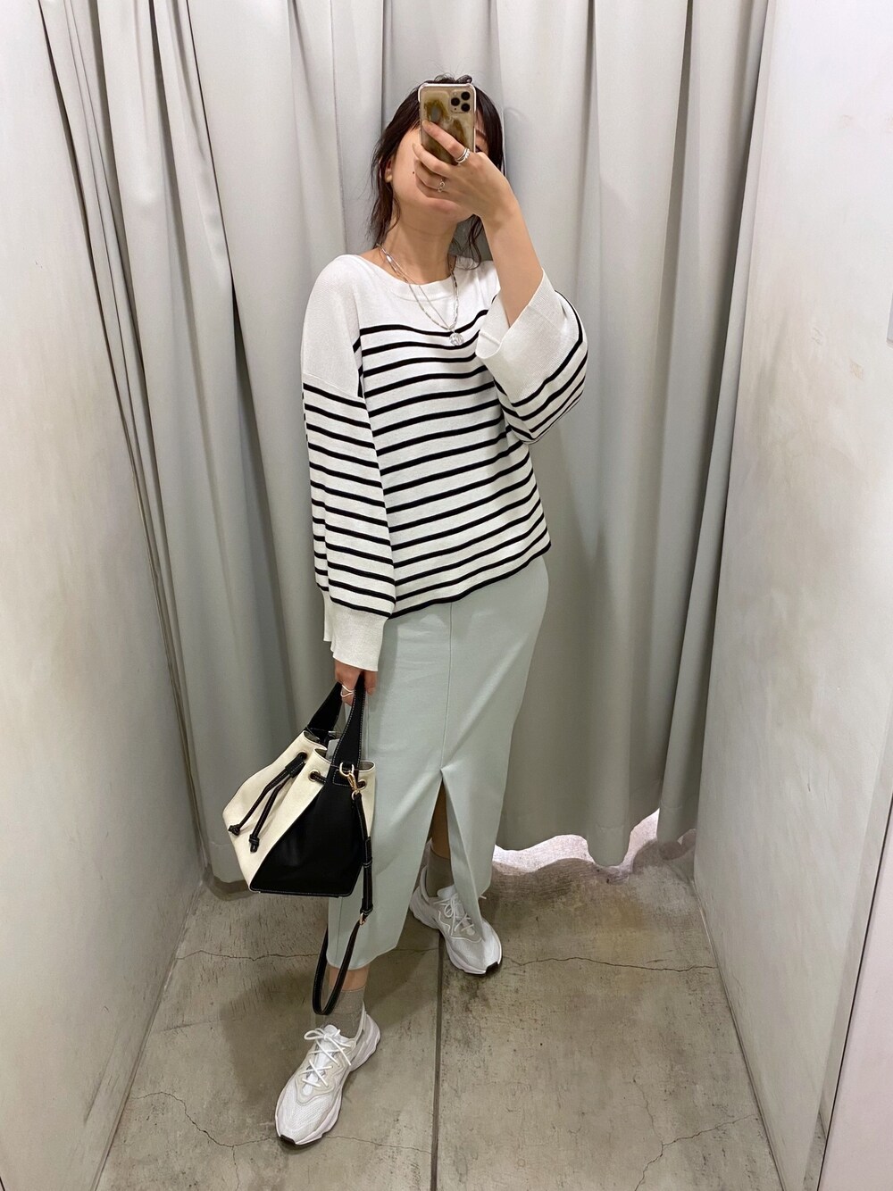 ブラック系のニット/セーター、ブルー系のスカート、ホワイト系のトートバッグを着用したレディースの冬コーディネートの4枚目の写真