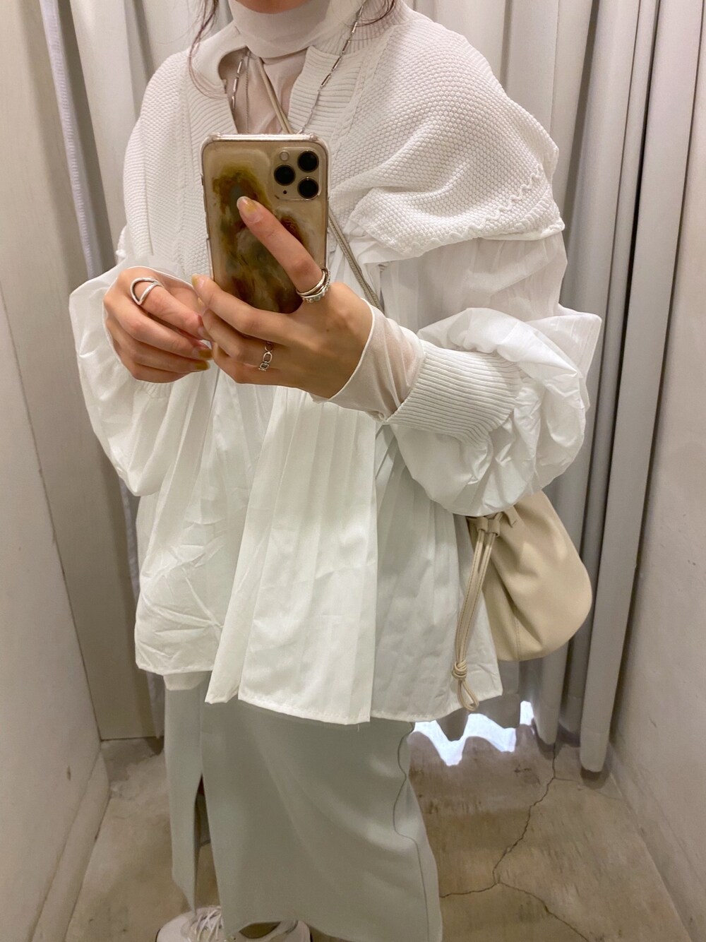 ホワイト系のニット/セーター、ブルー系のスカート、ベージュ系のショルダーバッグを着用したレディースの冬コーディネートの4枚目の写真