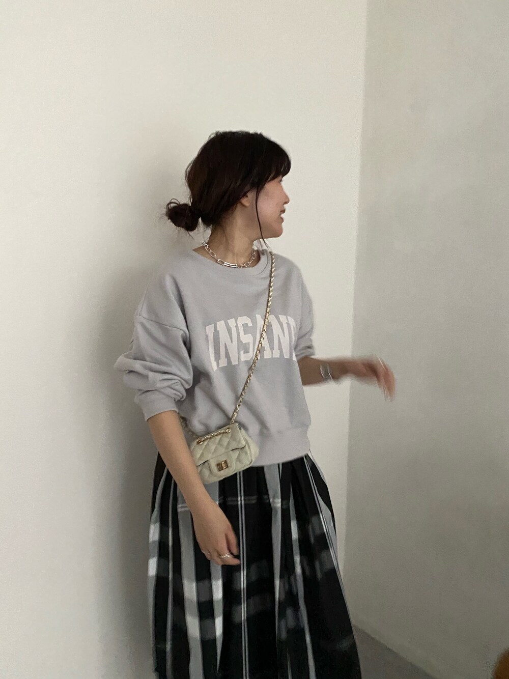 ベージュ系のTシャツ/カットソー、ブラック系のスカート、ホワイト系のショルダーバッグを着用したレディースの春コーディネートの3枚目の写真