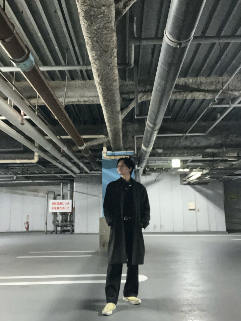 グリーン系のチェスターコート、ブラック系のスラックス、イエロー系のスニーカーを着用したメンズの春コーディネートの1枚目の写真