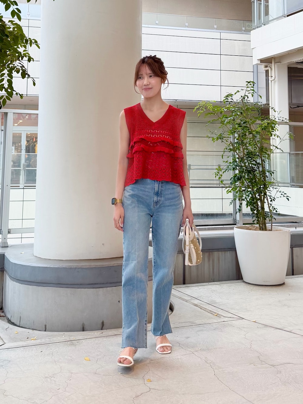 レッド系のニット/セーター、ブルー系のデニムパンツ、ホワイト系のショルダーバッグを着用したレディースの夏コーディネートの1枚目の写真