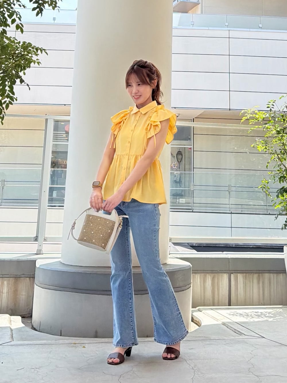 イエロー系のシャツ/ブラウス、ホワイト系のショルダーバッグ、ブルー系のデニムパンツを着用したレディースの夏コーディネートの1枚目の写真