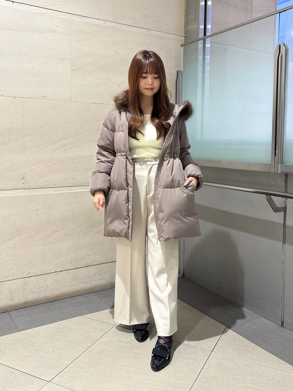 グレー系のその他パンツ、ブラウン系のダウンジャケット/コート、ホワイト系のニット/セーターを着用したレディースの秋コーディネートの1枚目の写真