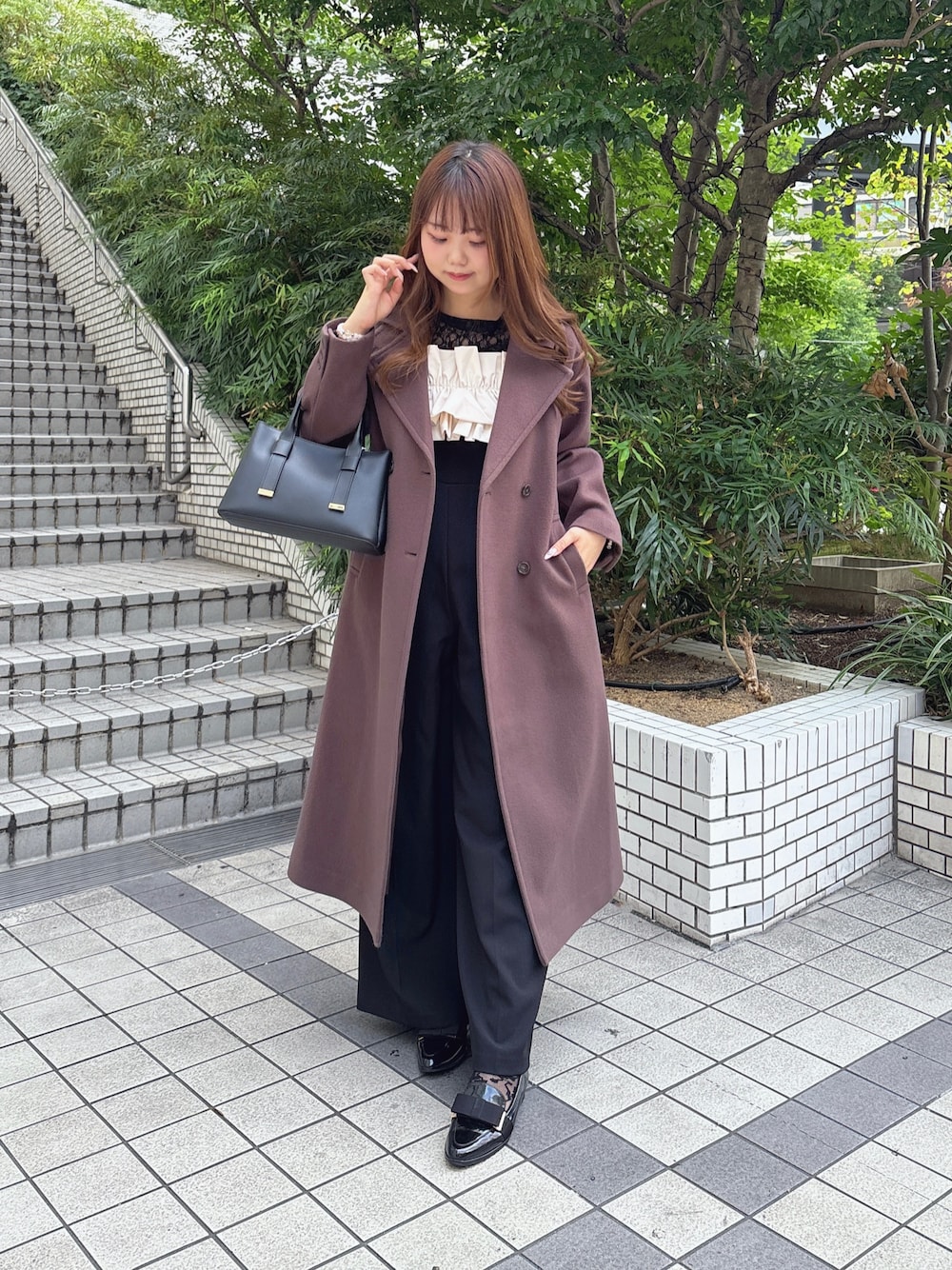 ブラウン系のチェスターコート、ブラック系のつなぎ/オールインワン、ブラック系のTシャツ/カットソーを着用したレディースの秋コーディネートの1枚目の写真
