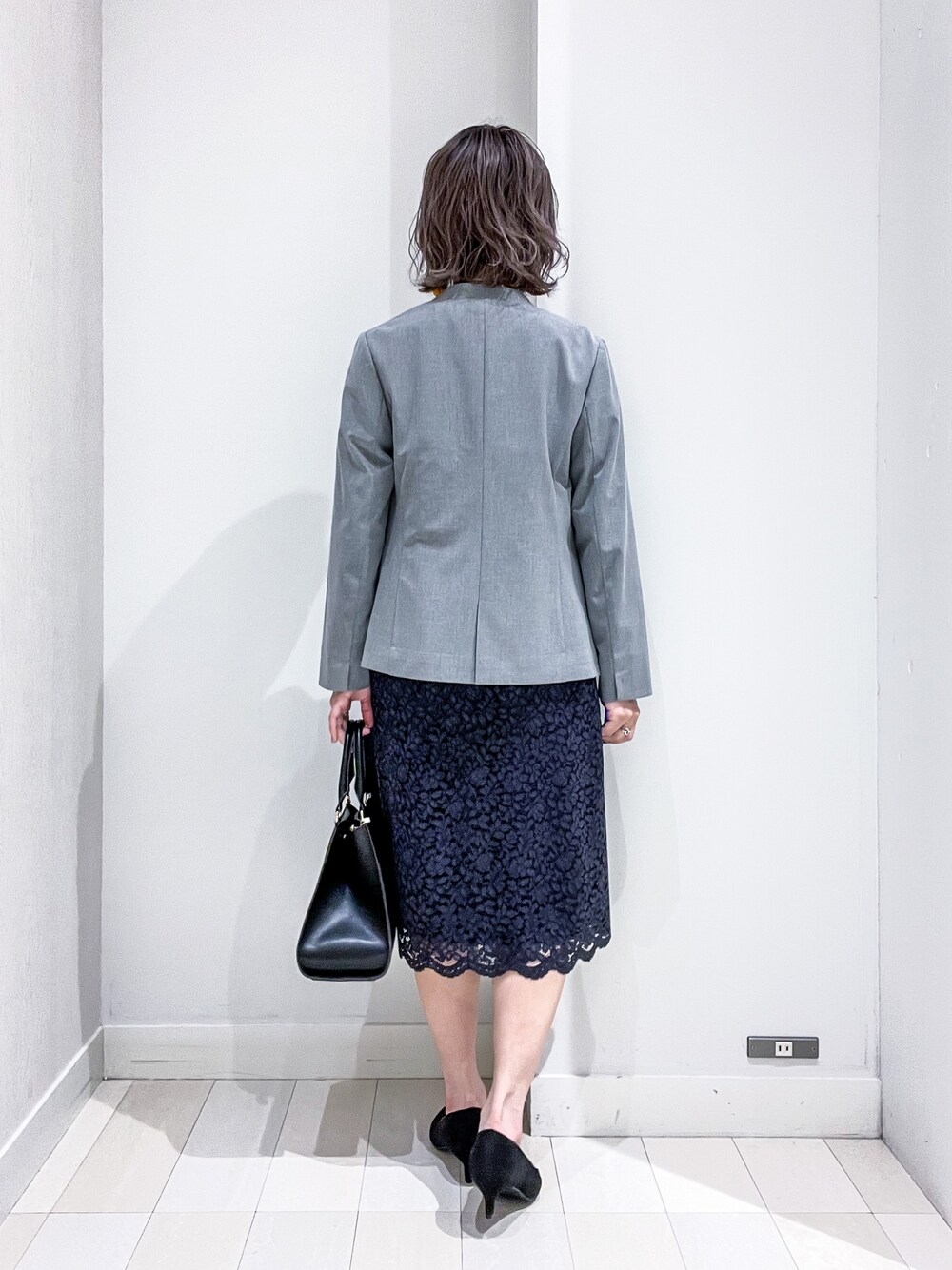 ブルー系のシャツ/ブラウス、グレー系のノーカラージャケット、ブルー系のスカートを着用したレディースの冬コーディネートの2枚目の写真