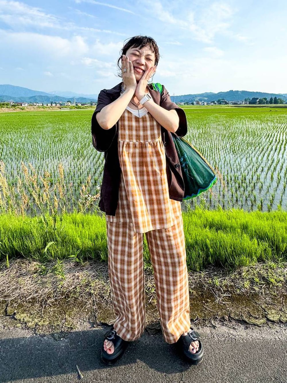 ホワイト系のタンクトップ、ブラック系のサンダル、ブラウン系のテーラードジャケットを着用したレディースの夏コーディネートの1枚目の写真