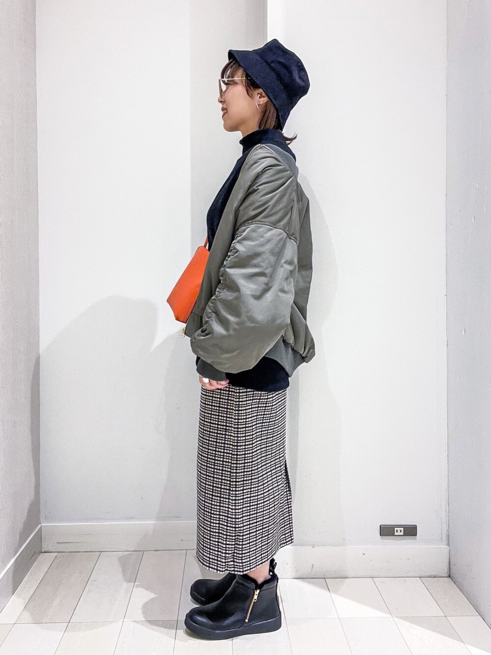 ブラック系のスウェット、グリーン系のMA-1、オレンジ系のショルダーバッグを着用したレディースの冬コーディネートの2枚目の写真