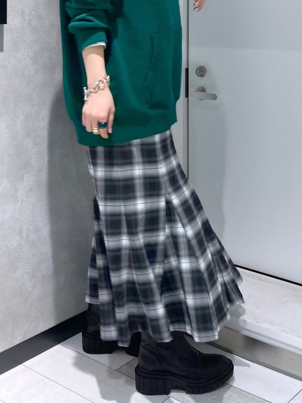 グリーン系のパーカー、ブラック系のスカート、ブラック系のブーツを着用したレディースの冬コーディネートの3枚目の写真