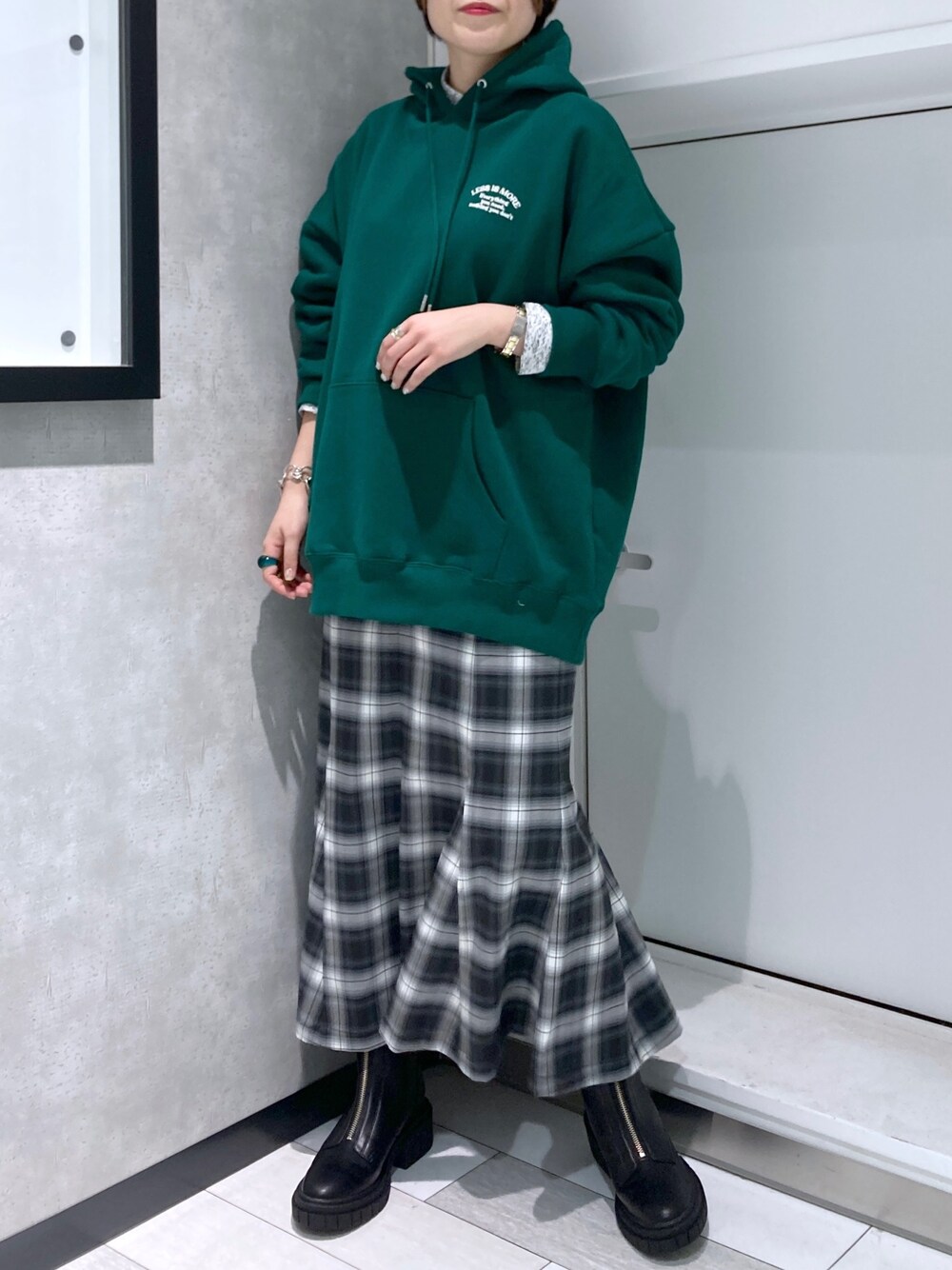 グリーン系のパーカー、ブラック系のスカート、ブラック系のブーツを着用したレディースの冬コーディネートの4枚目の写真