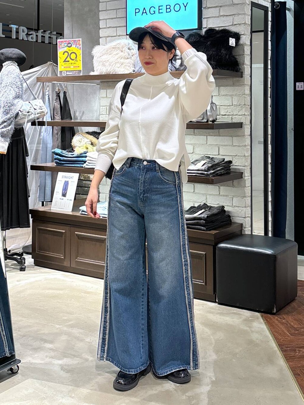 ホワイト系のニット/セーター、ブラック系のショルダーバッグ、ブルー系のデニムパンツを着用したレディースの冬コーディネートの1枚目の写真