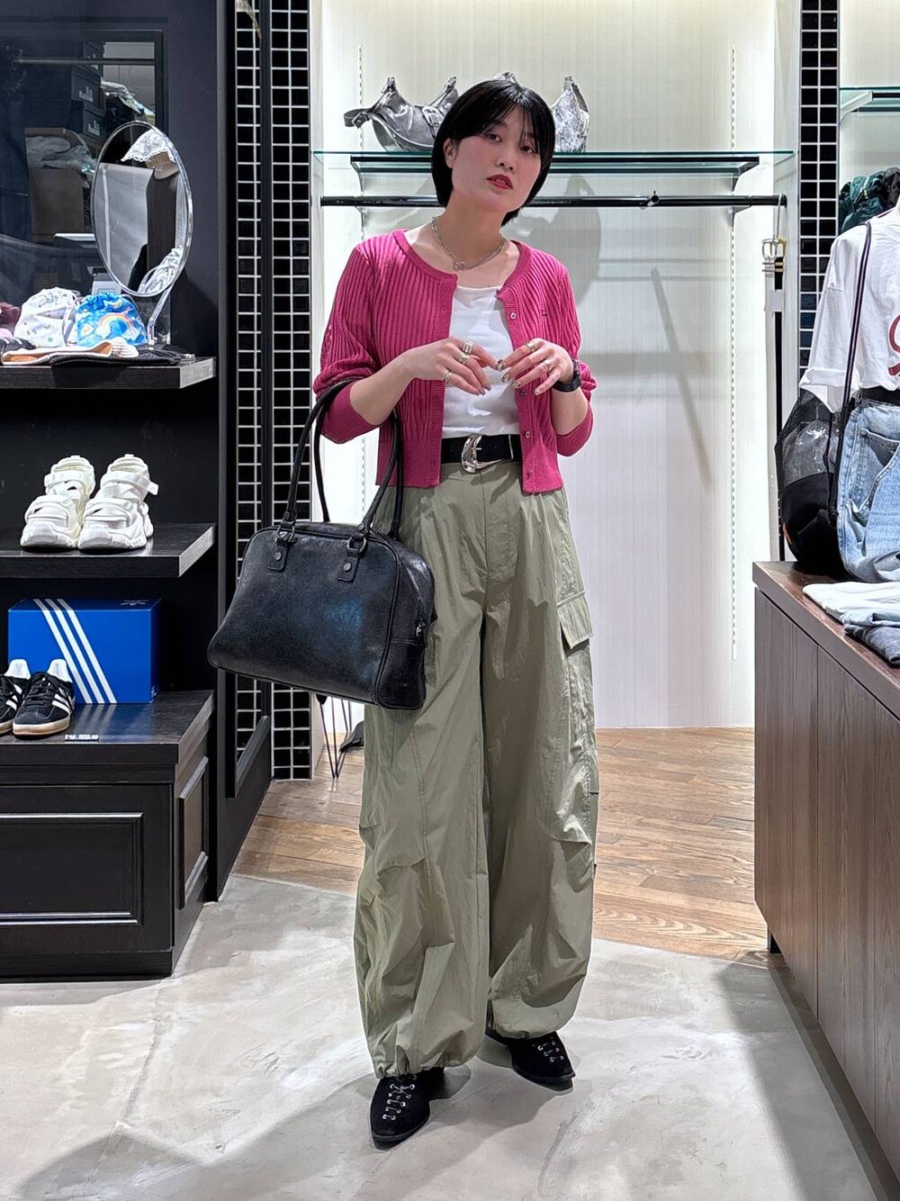 ブラック系のボストンバッグ、ブラック系のパンプス、グリーン系のカーゴパンツを着用したレディースの春コーディネートの1枚目の写真